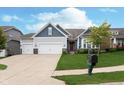 Charming home showcasing a three-car garage, green lawn, dark red front door, and tidy landscaping at 4196 Parliament Way, Avon, IN 46123