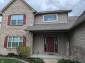 Close up of brick and vinyl siding with red front door and tasteful landscaping at 561 Prince Dr, Greenwood, IN 46142