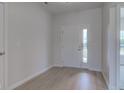 Bright foyer featuring light wood floors and a white front door with glass panes at 9182 Mulligan Ct, Elwood, IN 46036