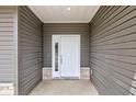 View of the white front door with glass panes and gray siding on a covered front porch at 9182 Mulligan Ct, Elwood, IN 46036