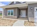 Close-up of the front porch with gray siding and a white front door with glass panes at 9182 Mulligan Ct, Elwood, IN 46036