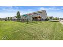 Large fenced backyard featuring a playset and covered patio, perfect for outdoor enjoyment at 11003 Liberation Trce, Noblesville, IN 46060