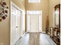 Bright foyer featuring a front door with sidelights, gray wood-look tile flooring, and stylish decor at 11958 Logan Hunter Trl, Noblesville, IN 46060