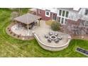 Aerial view of the outdoor living space featuring a stone patio with seating, a fire pit, and an outdoor kitchen at 12030 Auburn Creek, Zionsville, IN 46077