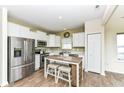Cozy kitchen with stainless steel appliances, white cabinetry, laminate floor, and eat-in island with stools at 1455 Bigleaf Dr, Sheridan, IN 46069