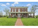 Beautiful brick home with a wide, inviting front porch and meticulous landscaping along a brick walkway at 1901 S Old State Road 67, Paragon, IN 46166