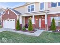 Inviting front porch with white columns, red door, well-kept landscaping, and a cozy seating area at 1907 Wedgewood Pl, Avon, IN 46123