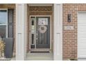 Close-up of a home's black front door framed by white trim, showcasing a decorative wreath and brick surround at 2736 Victory Dr, Columbus, IN 47203