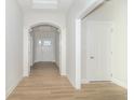 Bright, open hallway featuring elegant archways, white trim, and modern wood-look flooring at 3601 S Meadows Ln, New Palestine, IN 46163