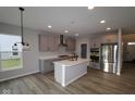 Modern kitchen with stainless steel appliances, a center island, light gray cabinets, and hardwood floors at 4952 Cinnabar Trl, Brownsburg, IN 46112