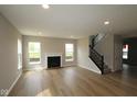 Bright living room featuring a fireplace, large windows, and hardwood floors and black staircase at 4960 Cinnabar Trl, Brownsburg, IN 46112