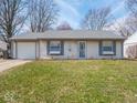 Well-kept single-story home featuring a tidy lawn, attached garage and charming light blue shutters at 5512 Straw Hat Dr, Indianapolis, IN 46237