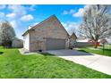 Angle view of a brick home with a garage, complemented by a green lawn at 701 Downing Dr, Greenwood, IN 46143