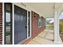 Close-up of the front door and covered porch with brick accents and a welcoming entrance at 7048 Millet Ln, Avon, IN 46123