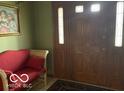 Inviting foyer with hardwood front door and a decorative love seat at 7664 Lincoln Trl, Plainfield, IN 46168