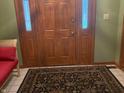 Classic wood front door with decorative glass sidelights and a patterned area rug at the entrance at 7664 Lincoln Trl, Plainfield, IN 46168