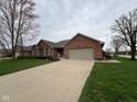 Single-story red brick home with a two-car garage, green lawn, and mature trees at 1066 Woodridge, Brownsburg, IN 46112
