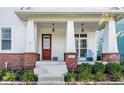 Inviting front porch with stylish brick accents and a pop of color from the red front door at 1401 Farmhouse Dr, Westfield, IN 46074
