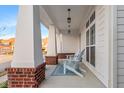 Inviting front porch with brick accents, classic white columns, stylish lighting, and comfortable seating area at 1401 Farmhouse Dr, Westfield, IN 46074