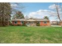 Single-story brick home features colorful shutters, landscaped yard, and inviting entrance at 1526 Chapman Dr, Greenfield, IN 46140