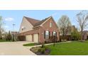 Brick home featuring a three-car garage, nice landscaping, and a well-maintained lawn at 1559 Redsunset Dr, Brownsburg, IN 46112