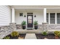 Inviting front porch features stone accents, sleek black front door, and elegant potted plants at 19983 Chatham Green Dr, Westfield, IN 46074