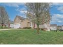 View of the tan, two-story house on a grassy hill with a quaint front porch and white trim at 2889 Grimes Way, Columbus, IN 47201
