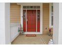 Close-up of a vibrant red front door with sidelights, charming decor, and white trim at 2889 Grimes Way, Columbus, IN 47201