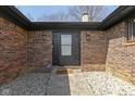 Covered brick entryway with black front door, modern sconces, and manicured gravel landscaping at 5344 Tincher Rd, Indianapolis, IN 46221