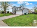 View of a two-story home with well-kept lawn, a two-car garage, and blue sky above at 594 N Shore Blvd, Franklin, IN 46131