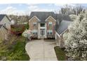 Charming two-story brick home featuring a two-car garage, basketball hoop, and meticulously maintained lawn with flowering tree at 805 Harvest Lake Dr, Brownsburg, IN 46112
