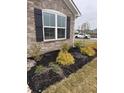 Close-up of newly installed landscaping with dark mulch, small shrubbery, and decorative rock at 99 Gnarled Oak Ln, Whiteland, IN 46184