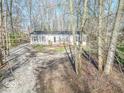 Single-story house featuring a front porch, gravel driveway, and surrounded by mature trees at 10614 W Hickory Ct, Quincy, IN 47456