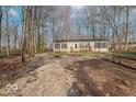 Single-story house featuring a front porch, gravel driveway, and mature trees at 10614 W Hickory Ct, Quincy, IN 47456