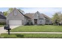 Beautifully landscaped front yard with a well-maintained lawn and charming light brick home at 11930 Pebblepointe Pass, Carmel, IN 46033