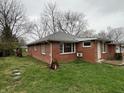 Back of house shows brick exterior with grassy backyard and some trees at 1509 N Mann Ave, Muncie, IN 47304
