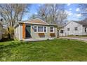 This home features light green siding, a concrete porch, healthy green lawn and a gravel drive on the side at 1836 N Riley Ave, Indianapolis, IN 46218