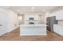 Open-concept kitchen featuring white cabinetry, stainless steel appliances, quartz counters and hardwood floors at 18769 Moray St, Westfield, IN 46074