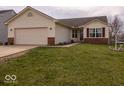 Inviting single-story home with a two-car garage, green lawn, and attractive landscaping at 2179 W Van Arsdall Ct, Columbus, IN 47201