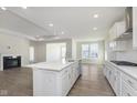 Open concept kitchen with a white island, stainless steel appliances, and hardwood floors next to a fireplace at 2766 Ruffian Dr, Westfield, IN 46074
