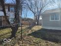 View of the backyard featuring a chain-link fence, mature trees, and lush green grass at 3844 Esquire Ct, Indianapolis, IN 46226