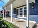Spacious porch featuring a view of the surrounding neighborhood, sturdy white columns, and dark blue siding at 46 N Denny St, Indianapolis, IN 46201