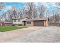 Split-level home with attached garage, spacious driveway, and large gravel parking area at 516 Hanover Dr, Anderson, IN 46012