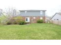 View of the rear exterior of the house featuring a brick facade, door, and a spacious backyard at 7421 Rogers Dr, Indianapolis, IN 46214