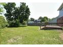 Expansive backyard with a lush lawn, mature trees, and a wooden deck, perfect for outdoor entertaining at 7421 Rogers Dr, Indianapolis, IN 46214
