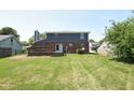 View of the home's rear exterior, deck, and large, grassy backyard perfect for outdoor activities at 7421 Rogers Dr, Indianapolis, IN 46214