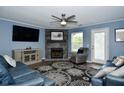 Cozy living room with fireplace, mounted TV, modern ceiling fan, and comfortable seating on a decorative area rug at 10622 Young Lake Dr, Indianapolis, IN 46239