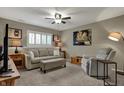 Cozy living room with comfortable seating, neutral walls, a ceiling fan and a window with plantation shutters at 12658 Watford Way, Fishers, IN 46037