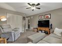 Comfortable living room featuring neutral walls, ceiling fan, and an entertainment center with a large television at 12658 Watford Way, Fishers, IN 46037