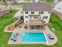 Aerial view of a backyard with a pool, patio with dining, lounge furniture, and green lawn at 13974 Nina Dr, Carmel, IN 46074